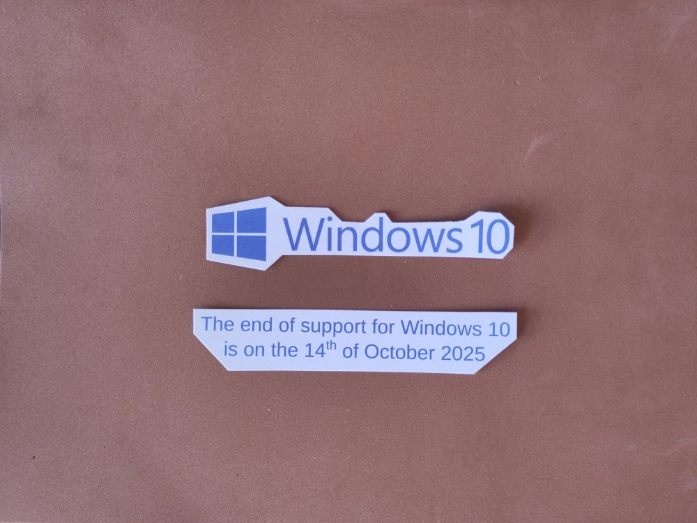 Image of a Windows 10 sticker accompanied by a second sticker that says the end of support for Windows 10 is on the 14th of October 2025. These are against a brown background. The video tag that this image is embedded in shows the same but with two hands bringing each sticker into view from the sides of the screen